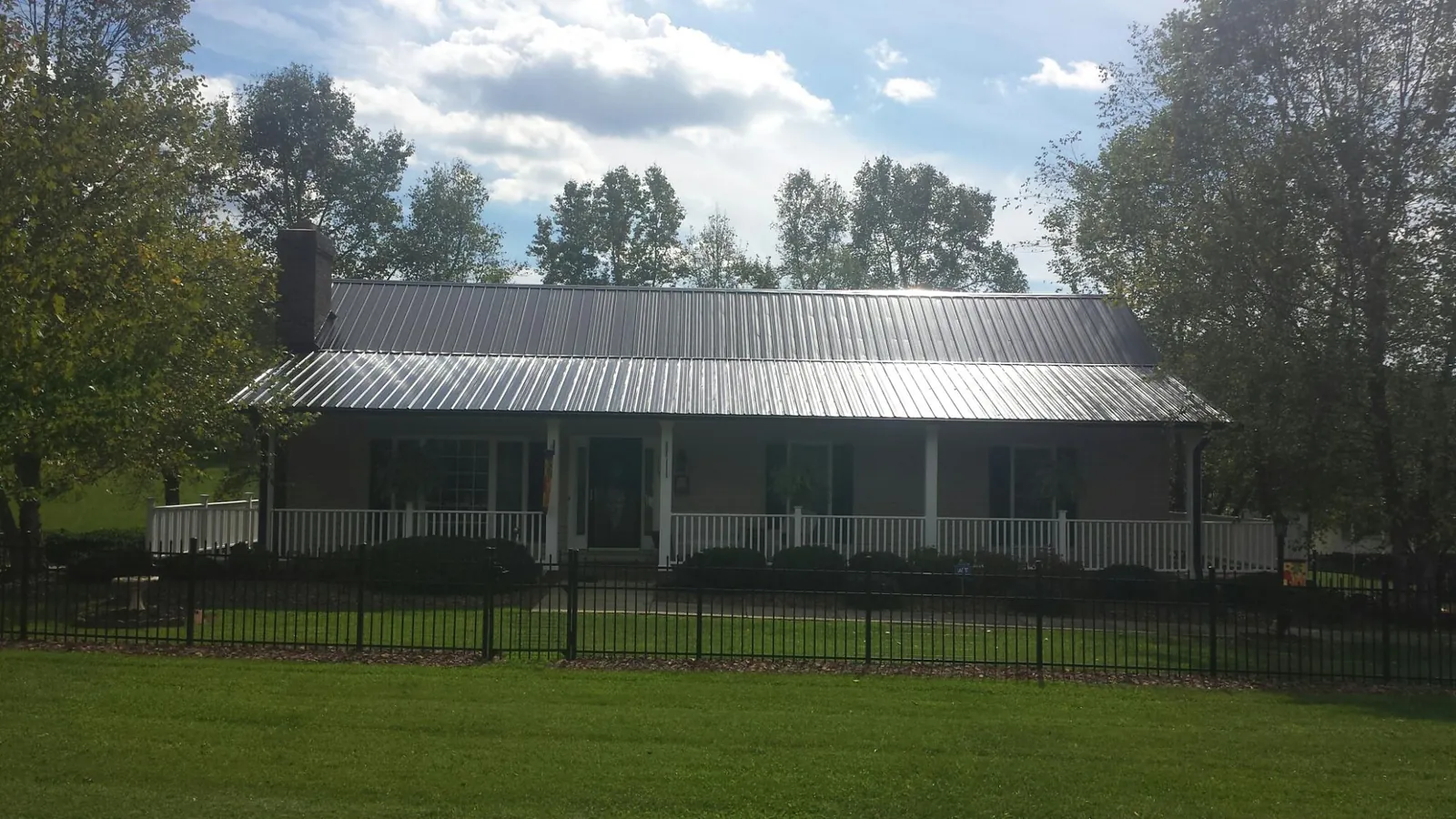 Gray metal roof on a brick ranch with a full width front porch — Gutter Guard Installation work by our crew in Martin